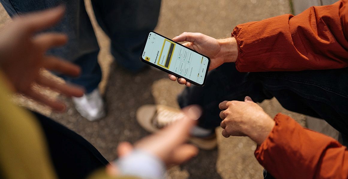 Nahaufnahme einer Person, die im Freien die Schweizer Post-App auf ihrem Smartphone nutzt.