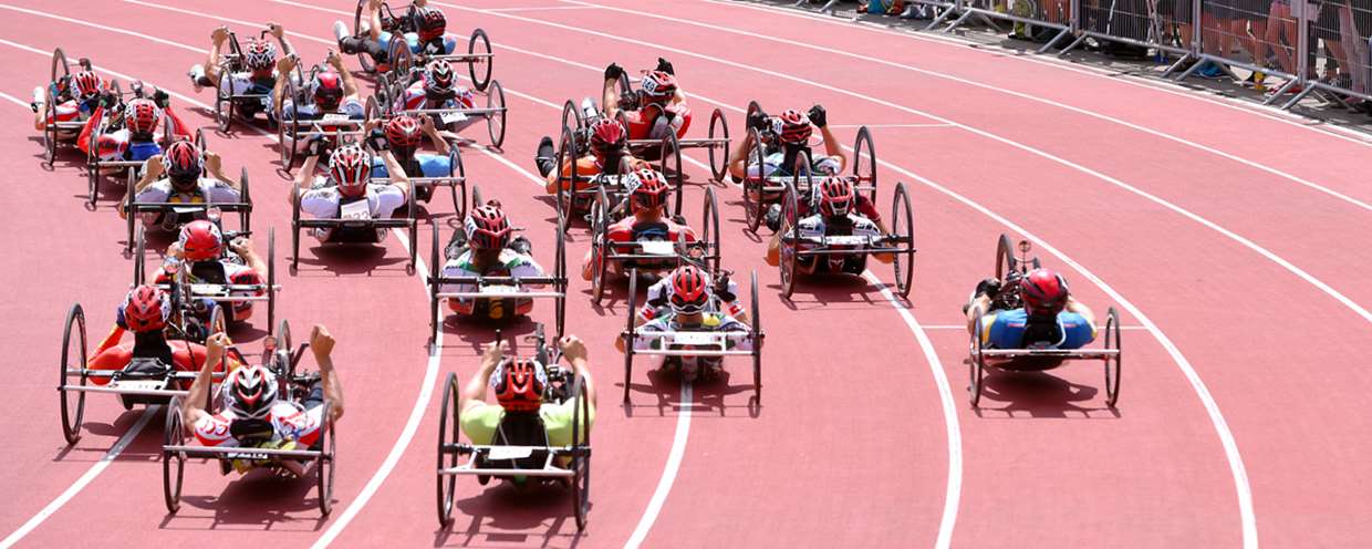 Das Stimmungsbild zeigt rund 20 Rollstuhlfahrer, die ein Rennen mit dem Handbike absolvieren auf der Bahn der Sport Arena Nottwil.